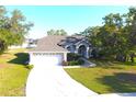 Aerial view of a charming home with a two-car garage, landscaped yard, and mature trees at 63 Forest Wood Ct, Spring Hill, FL 34609