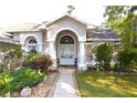 Close up view of the front entrance to the home with columns and manicured landscaping at 63 Forest Wood Ct, Spring Hill, FL 34609