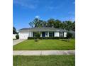 Inviting single-story white home with a well-maintained lawn, attached garage, and a charming blue front door at 7229 Northbridge Blvd, Tampa, FL 33615
