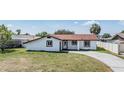 Charming single-story home with white exterior, red roof, and well-manicured lawn at 8705 Tahiti Ln, Tampa, FL 33615