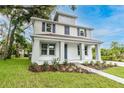 Inviting two-story home with a spacious front porch, featuring well-kept landscaping and fresh green grass at 114 W Plymouth St, Tampa, FL 33603
