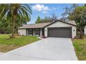 Single-story home with a manicured lawn, lush landscaping, long driveway and attached two-car garage at 12601 Stone House Loop, Hudson, FL 34667