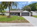 Well-maintained single Gathering home with a manicured lawn, palm tree, and an attached two-car garage at 12601 Stone House Loop, Hudson, FL 34667