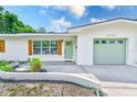 Close up of charming single-story home with light-green garage and front door, and wooden shutters at 2220 Calexico S Way, St Petersburg, FL 33712