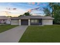 Charming single-story home with an attached garage and a spacious front yard at sunset at 2444 Magellan Ave, Spring Hill, FL 34608