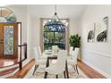 Bright dining room with a glass table set, chandelier, and large window overlooking the lush landscaping at 2513 Buckhorn Run Dr, Valrico, FL 33596