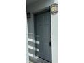 A close-up of the grey front door with the house number 4127 and outdoor lighting at 4127 Dolphin Dr # 4127, Tampa, FL 33617