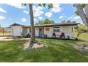 Charming single-story home with a well-maintained lawn, landscaping, and cozy front porch with red Adirondack chairs at 7494 7Th N St, St Petersburg, FL 33702