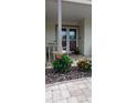 Close-up of a cozy front porch featuring brick flooring, comfortable seating, and vibrant landscaping for added curb appeal at 9335 Stonewall, New Port Richey, FL 34655
