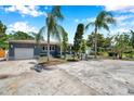Well-maintained home with mature palm trees, a driveway, an attached garage and lush landscaping at 936 Alcazar Way S, St Petersburg, FL 33705