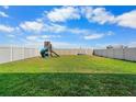 Spacious backyard featuring a playground, a fire pit, and a white vinyl fence at 11079 Linden Depot Rd, San Antonio, FL 33576