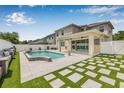 This backyard features a covered patio, private pool, stylish tile and turf combination, and white privacy fence at 14718 Rocky Brook Dr, Tampa, FL 33625