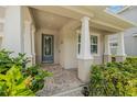 Inviting front porch with classic columns, brick pavers, and lush landscaping creates a welcoming entrance at 14718 Rocky Brook Dr, Tampa, FL 33625