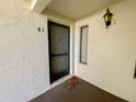 Front entryway featuring a welcome mat, exterior sconce, and textured wall finish at 2643 Pine Ridge S Way # A1, Palm Harbor, FL 34684