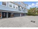 Exterior view of a light blue three-story townhome with multiple garages and a brick driveway at 3111 W De Leon St # 8, Tampa, FL 33609