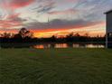 Scenic backyard view overlooking a tranquil lake, capturing a vivid sunset reflecting on the water at 33030 Major Oak Dr, Wesley Chapel, FL 33545