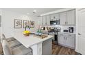 Stylish kitchen featuring gray cabinets, stainless appliances, quartz counters and bar stool seating at 4587 Georgia Ave, North Port, FL 34288