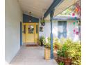 Inviting front porch with a yellow door, surrounded by planters, colorful decorations, and a patterned tile floor at 7903 Heather Ct, Tampa, FL 33634