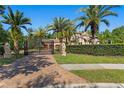 Elegant gated entrance with lion statues, lush landscaping, and a beautiful brick driveway at 1102 Merry Water Dr, Lutz, FL 33548