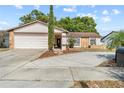 Inviting home featuring a well-manicured lawn, charming stone details, and an attached two-car garage at 11318 Stoneybrook Path, Port Richey, FL 34668