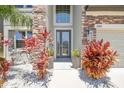 The home's entryway features a glass paneled front door, stone accents, and decorative landscaping at 11416 Alachua Creek Ln, Riverview, FL 33579
