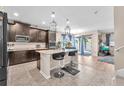 Modern kitchen with dark cabinets, a center island with bar stools, and stylish pendant lighting at 11525 Scarlet Ibis Pl, Riverview, FL 33569