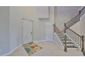 Bright foyer with a staircase featuring wooden handrails and black iron balusters, plus neutral tile flooring at 11909 Climbing Fern Ave, Riverview, FL 33579