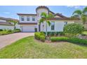 Beautifully landscaped front yard with lush green grass, palm trees, and decorative shrubs enhancing curb appeal at 11909 Climbing Fern Ave, Riverview, FL 33579