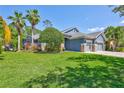 Well-maintained lawn featuring a beautiful blue home with a three-car garage, and lush landscaping at 14727 Tudor Chase Dr, Tampa, FL 33626