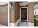 Close-up of a brown front door framed by stucco walls and a decorative lantern at 2131 River Turia Cir, Riverview, FL 33578