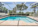 Inviting screened-in pool area featuring a waterfall and serene views of the surrounding landscape at 5429 Legend Hills Ln, Spring Hill, FL 34609