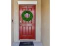 Inviting red front door adorned with a green wreath and 'Welcome' doormat at 5457 Leslie Canyon Dr, Wimauma, FL 33598