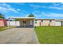 A quaint single-story home featuring a carport, manicured lawn, and freshly painted exterior under a bright blue sky at 6010 Blossom Ave, Tampa, FL 33614
