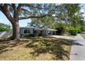 Single-story home with a covered carport, mature trees, and a partially shaded lawn, perfect for outdoor living at 920 16Th Sw Ave, Largo, FL 33770