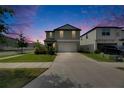 Attractive two-story home featuring a well-maintained lawn and concrete driveway at twilight at 9907 Spanish Lime Ct, Riverview, FL 33578