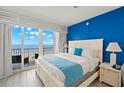 Bright bedroom with a comfortable king bed, blue accent wall, and balcony access with ocean views at 9980 Gulf Blvd # 603, Treasure Island, FL 33706