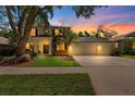 Charming two-story home features a well-manicured lawn and an attached three-car garage during sunset at 1133 Split Silk St, Valrico, FL 33594