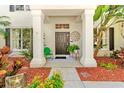 Inviting front porch features stately white columns, a decorative front door, and lush landscaping at 1133 Split Silk St, Valrico, FL 33594