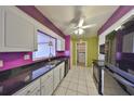Colorful kitchen with black appliances, a double sink, white cabinetry, and a view to the laundry room at 1207 Norwich Cir, Sun City Center, FL 33573