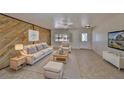 Inviting living room featuring a unique wood accent wall, neutral furniture, and a ceiling fan at 1207 Norwich Cir, Sun City Center, FL 33573