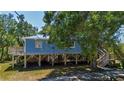 Elevated stilt home with wooden supports and staircase, set amidst a lush, green landscape at 1616 Lightfoot Rd, Wimauma, FL 33598