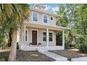 Beautiful two-story home with a welcoming front porch, surrounded by mature trees and lush greenery at 1913 W Pine St, Tampa, FL 33607