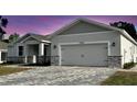Two-car garage with brick paver driveway, stone veneer and neutral color palette at 37533 Teri Ct, Dade City, FL 33525