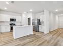 Modern kitchen featuring white cabinets, stainless steel appliances, an island, and wood-style floors at 4810 Prime Ter, North Port, FL 34286