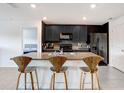 A kitchen island boasts barstool seating, granite countertops, stainless steel appliances, and a modern backsplash at 7929 Sail Clover Ln, Zephyrhills, FL 33540