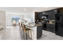 A modern kitchen boasts black cabinets, stainless steel appliances, and a granite countertop island with barstool seating at 7929 Sail Clover Ln, Zephyrhills, FL 33540