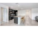 A contemporary kitchen features an island with seating, stainless steel appliances, and modern cabinetry with ample storage at 7929 Sail Clover Ln, Zephyrhills, FL 33540