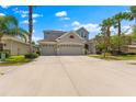 Home featuring a three-car garage, well-maintained landscaping, and a spacious driveway under a blue sky at 10511 Mistflower Ln, Tampa, FL 33647