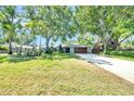 Charming home featuring a stone-accented facade, lush lawn and mature shade trees over the driveway at 1220 Pinellas Point S Dr, St Petersburg, FL 33705