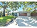 Inviting single story home with a stone-accented garage, pretty lawn, and mature shade tree at 1220 Pinellas Point S Dr, St Petersburg, FL 33705